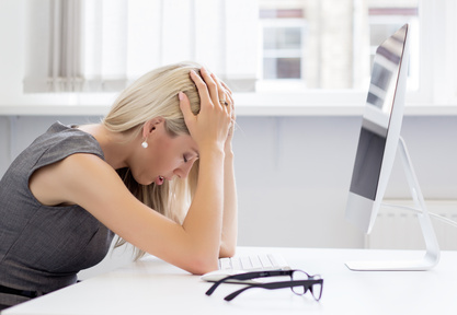 Overworked and tired young woman dealing with stress in front of a computer.