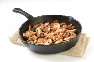 Sauteed mushrooms in a cast iron skillet on a white background