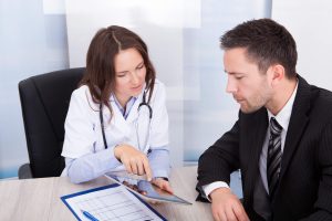 Young Female Doctor Showing Digital Tablet To Businessman ** Note: Shallow depth of field