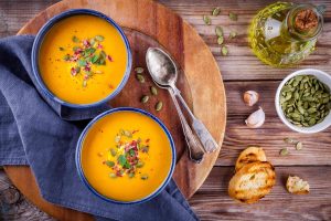 homemade autumn butternut squash soup with pumpkin seeds bacon and basil on wooden background