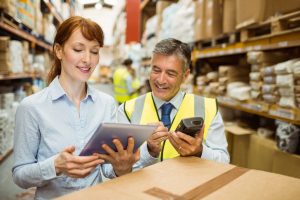 Warehouse managers looking at tablet pc in a large warehouse