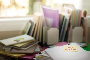 Do Now; Stack of Documents. Working or Studying at messy desk.